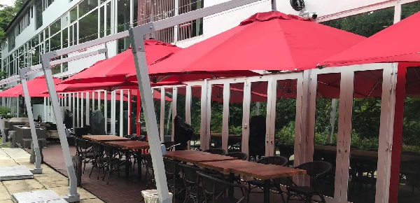 sombrillas rojas en voladizo que dan sombra a una terraza con mesas