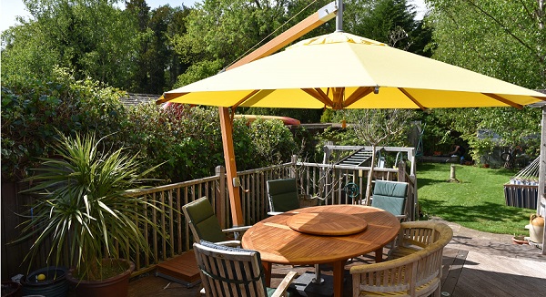 sombrilla amarilla de jardín con mesa ovalada en un patio
